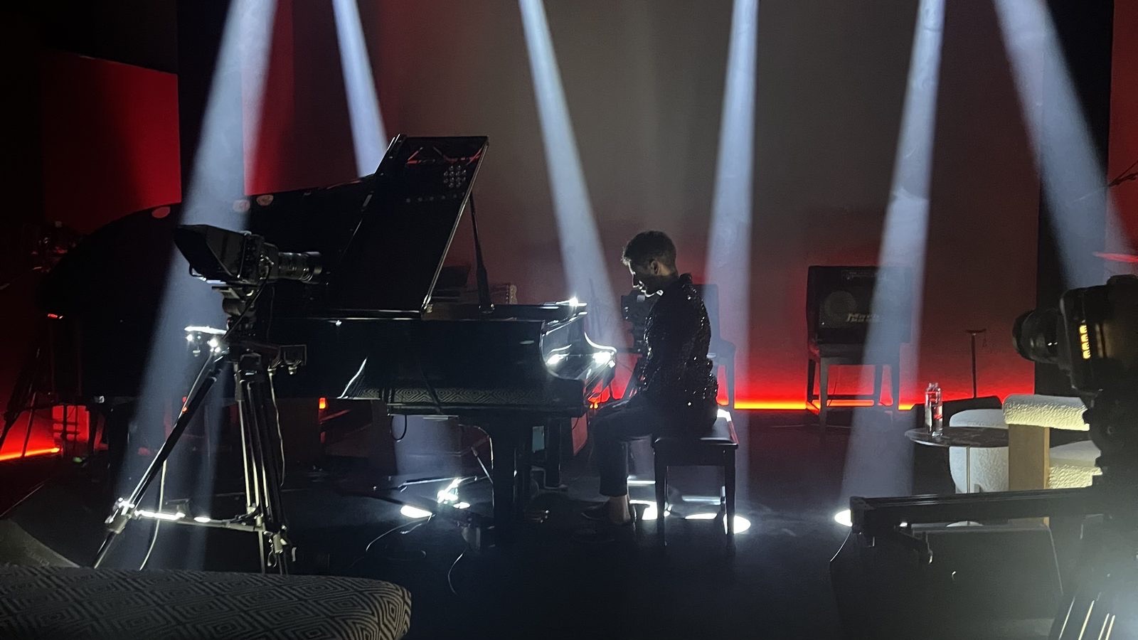 The Live Room set for a stream: a performer at the grand piano under moving-head beams, with cameras on tripods at both sides